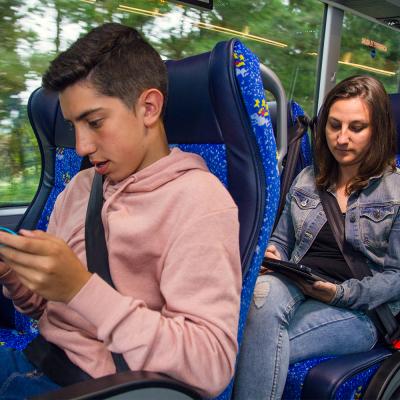Un neno e unha moza viaxando nun autobús de Monbus