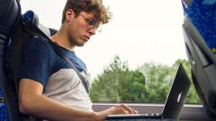 Un jeune travaille avec l’ordinateur pendant son voyage en autobus