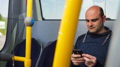 Usuario mirando o seu teléfono móbil nun autobús urbano de Monbus