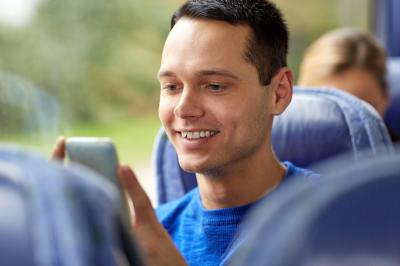 Guy checks his phone on a bus