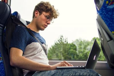 Young man working on his computer during a bus trip