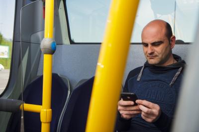 Un usager regarde son téléphone dans un autobus urbain de Monbus